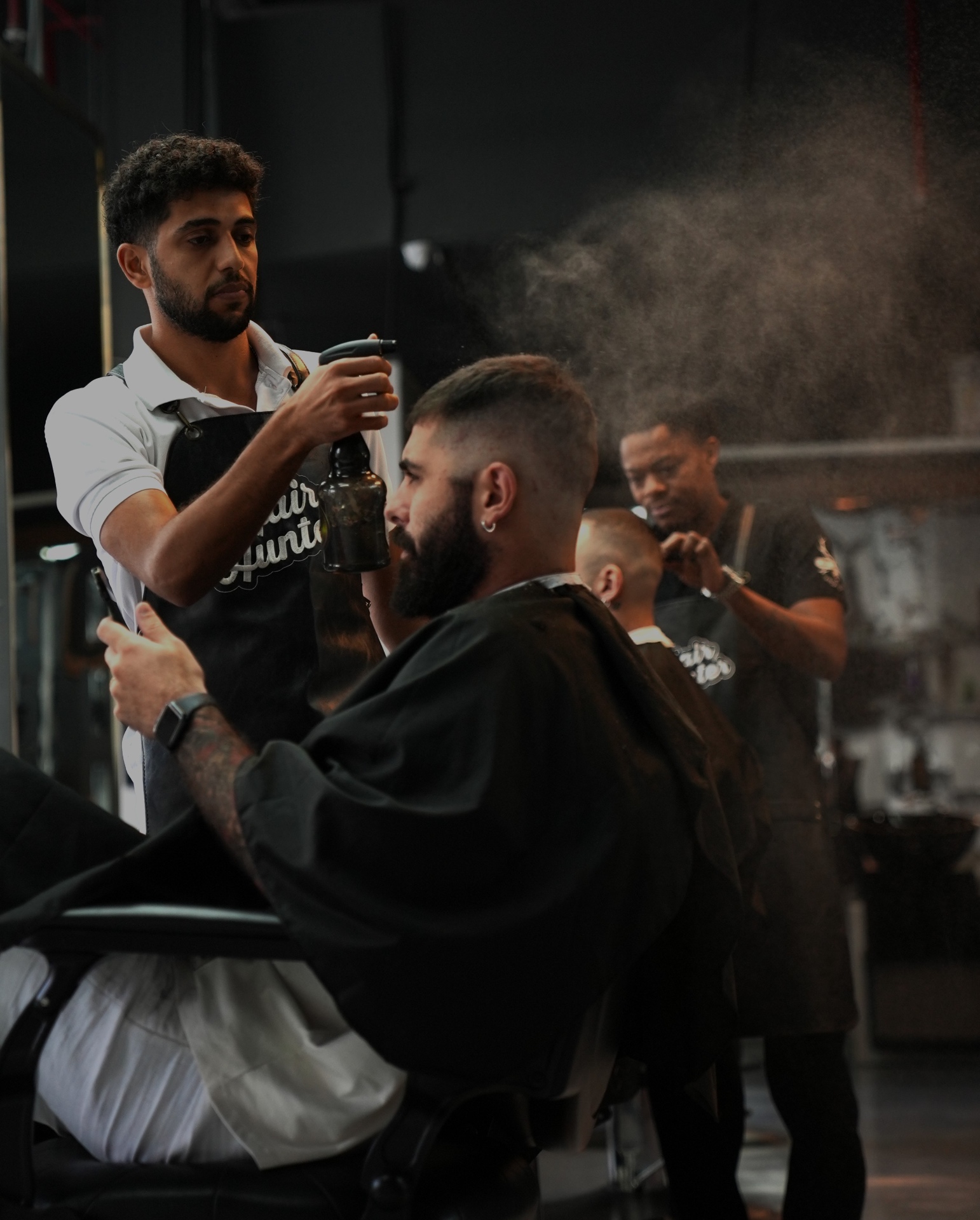 Barber misting a client through the chair