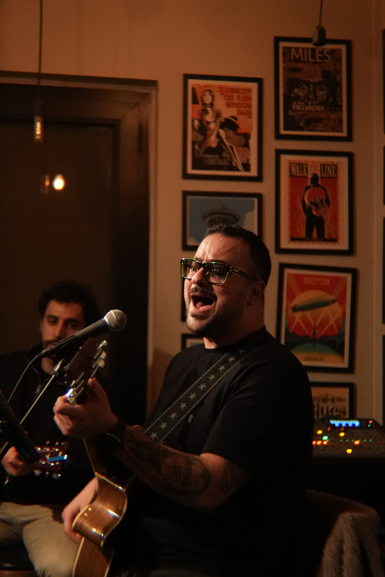 Live acoustic set in a posters-lined room